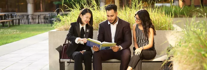 MMPA Students Reading Textbook, while sitting on a bench